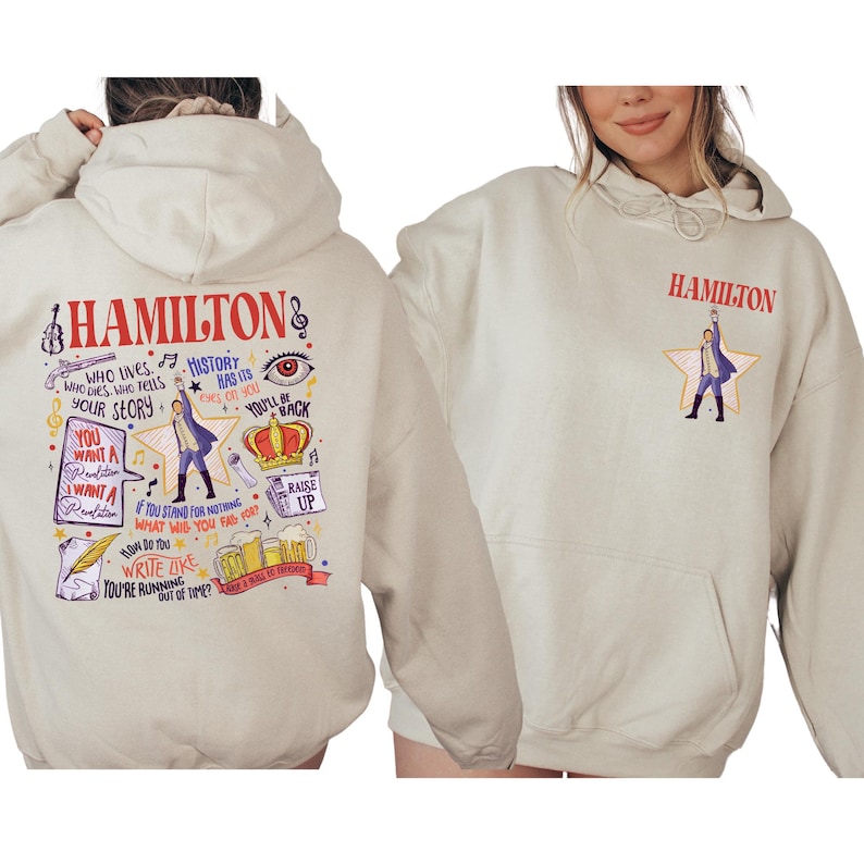 a person wearing a white hoodie with various colorful illustrations and text related to the musical Hamilton.
