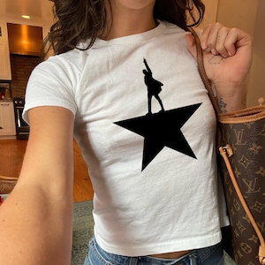 A person wearing a white t-shirt with a black silhouette of a person on a star.