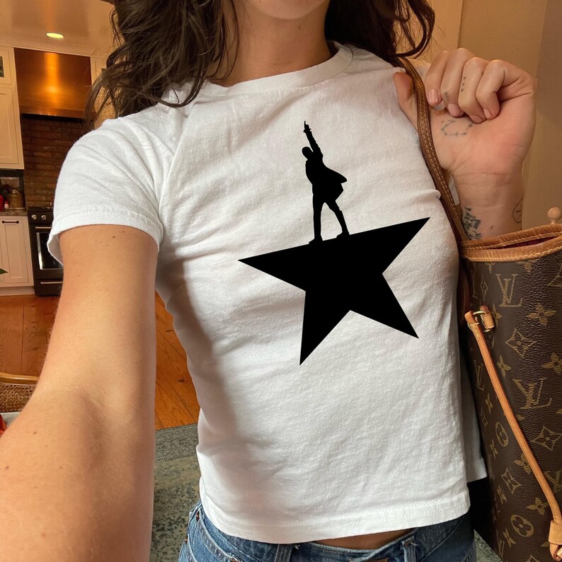 A person wearing a white t-shirt with a black silhouette of a person on a star.