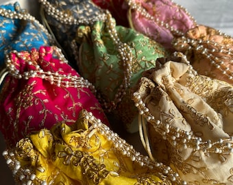 May include: A collection of colorful drawstring bags with pearl embellishments and gold embroidery. The bags are made of silk and are perfect for carrying small items.