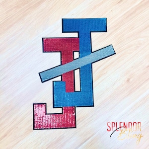 May include: A red, blue, and silver sequined patch with the letters "JT" in a stylized design. The patch is on a wood background with the text "Splendor Things" in gold lettering.