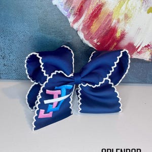 May include: A navy blue hair bow with white scalloped edges. The bow features the letters "LZ" in pink and blue. The bow is on a white surface with a colorful abstract painting in the background. The text "SPLENDOR Bling" is at the bottom.