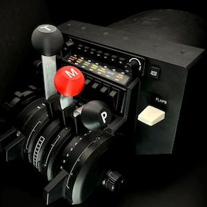 May include: Black flight simulator throttle quadrant with multiple levers and buttons. Features a red knob marked "M", a black knob marked "P", and a black knob marked "T". The panel includes labels for "AUTO PILOT" and "FLAPS".