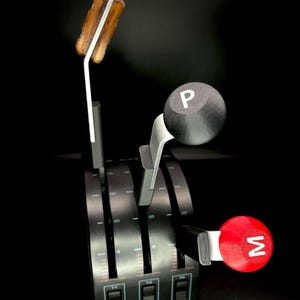 May include: A black throttle quadrant with three levers and a series of buttons. The levers have different colored handles: a wooden handle, a black handle with a white "P", and a red handle with a white "M".