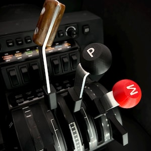 May include: Close-up of a black flight simulator throttle quadrant with three levers. One lever has a wooden handle, another has a black knob with a white "P", and the third has a red knob with a white "W". The text "IDIGFLIGHTSIM" is visible.