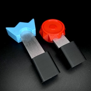 May include: Two metal tools with black handles and different coloured plastic tops. One top is blue and shaped like a crown, the other is red and round.