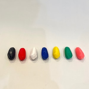 K&ouml;nnte beinhalten: Sieben kleine, eif&ouml;rmige St&uuml;cke Ton in verschiedenen Farben: Schwarz, Rot, Wei&szlig;, Blau, Gelb, Gr&uuml;n und Rosa.