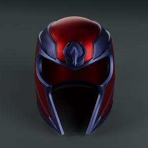 May include: A metallic helmet featuring a deep red finish on the crown and sides, accented by a dark blue frame that surrounds the eye opening and extends down the cheeks. A central blue crest sits prominently above the brow area.