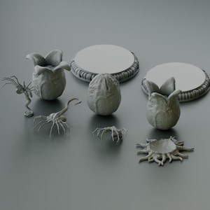 May include: A set of grey 3D printed alien creature figurines, including a facehugger, a chestburster, a queen, and a drone. The figurines are on a grey background.
