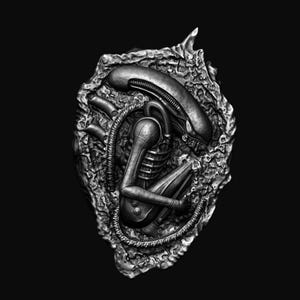 Puede incluir: Una escultura de una criatura extraterrestre negra y plateada en posición fetal dentro de una estructura rocosa. La escultura está detallada con líneas y texturas intrincadas.