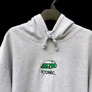 May include: A grey hooded sweatshirt with a green car graphic and the word "ICONIC." embroidered on the front.