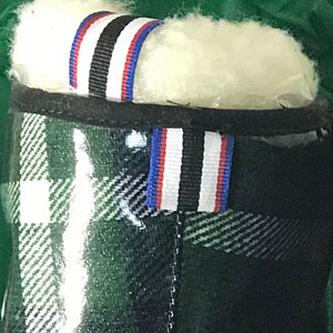 Puede incluir: Botas de lluvia de cuadros verdes, negros y blancos con un ribete de rayas negras, blancas y azules alrededor de la parte superior.