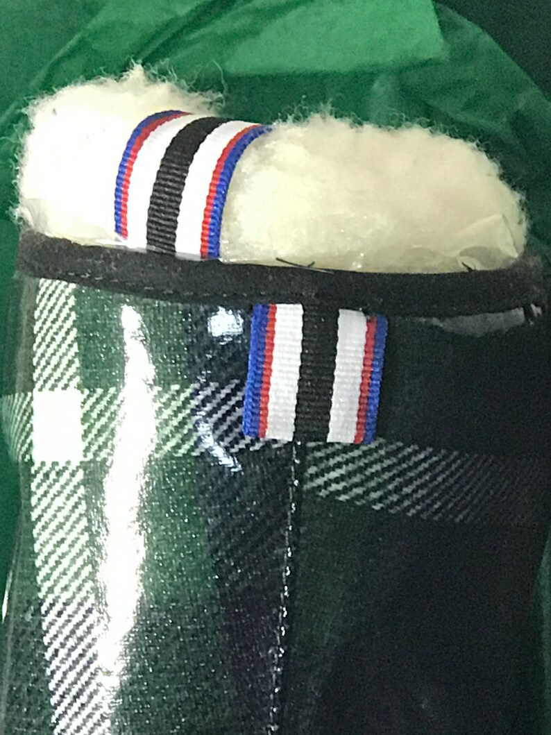 Puede incluir: Botas de lluvia de cuadros verdes, negros y blancos con un ribete de rayas negras, blancas y azules alrededor de la parte superior.