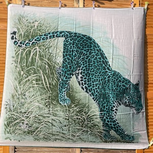 Puede incluir: Una bufanda verde y blanca con un gran diseño de estampado de leopardo verde. La bufanda tiene el texto "Panthere Noire" y "Hermes Paris".