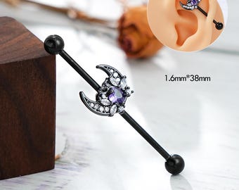 Puede incluir: Barbell industrial negro con un encanto de media luna adornado con cristales morados y transparentes. El barbell tiene un diámetro de 1,6 mm y una longitud de 38 mm.