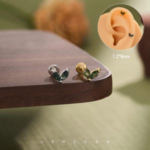May include: Two leaf-shaped stud earrings featuring marquise-cut green moss agate stones. One earring has a silver-tone metal base and the other has a gold-tone metal base. The text 1.2*8mm is visible near an ear model showing the earring placement.