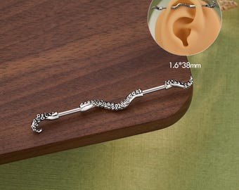 May include: A silver industrial barbell earring with an octopus tentacle design. The earring is 38mm long and features a curved bar with detailed tentacle ends and a textured body. The word "JEWSEEN" is printed at the bottom.