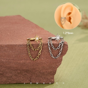 May include: Gold and silver-toned ear cuffs with starburst and chain details. The ear cuffs are shown on a brown surface. The text "JEWSEN" is visible at the bottom of the image. The ear cuffs measure 1.2mm x 8mm.