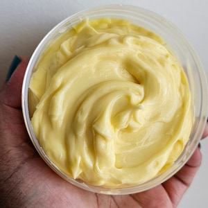 Peut inclure: Gros plan sur un r&eacute;cipient en plastique transparent rempli d'une substance cr&eacute;meuse jaune. La substance a une texture lisse et tourbillonnante.