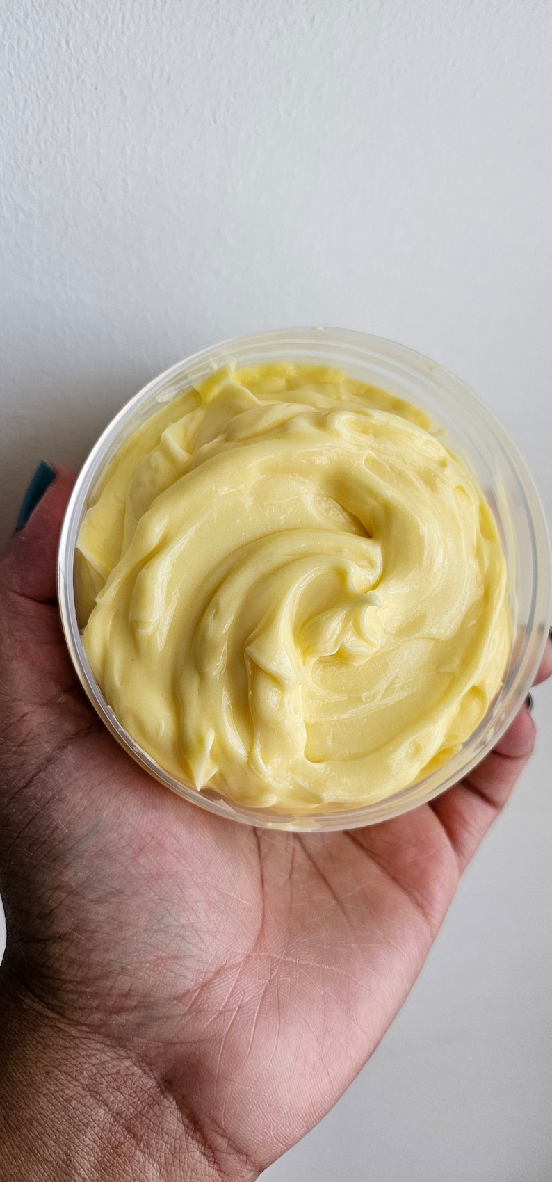 Peut inclure: Gros plan sur un r&eacute;cipient en plastique transparent rempli d'une substance cr&eacute;meuse jaune. La substance a une texture lisse et tourbillonnante.