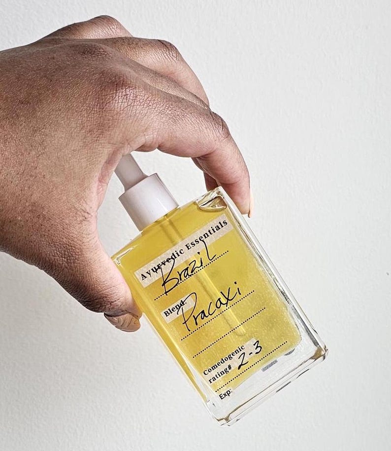 May include: A clear glass bottle with a yellow liquid inside. The bottle has a white dropper and a label that says "Ayurvedic Essentials Brazil Blend Pracaxi Comedogenic rating# 2-3 Exp."