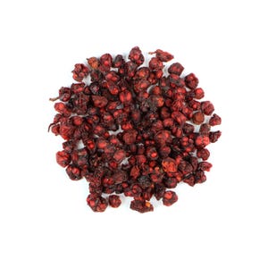 Pode incluir: Um monte de bagas de schisandra secas, vermelho escuro, contra um fundo branco. As bagas t&ecirc;m uma textura enrugada e uma cor profunda e rica, sugerindo que est&atilde;o maduras e prontas para uso. A imagem &eacute; uma vista de cima.