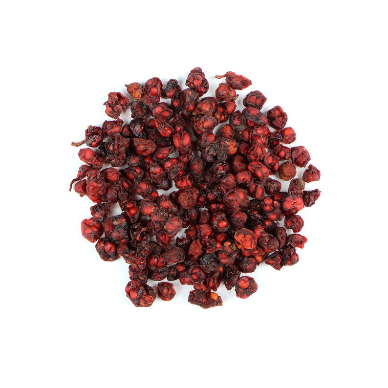 Pode incluir: Um monte de bagas de schisandra secas, vermelho escuro, contra um fundo branco. As bagas t&ecirc;m uma textura enrugada e uma cor profunda e rica, sugerindo que est&atilde;o maduras e prontas para uso. A imagem &eacute; uma vista de cima.