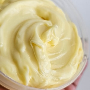 Peut inclure: Gros plan sur un r&eacute;cipient rempli d'une cr&egrave;me lisse de couleur jaune p&acirc;le. La cr&egrave;me est &eacute;paisse et pr&eacute;sente un motif en spirale.
