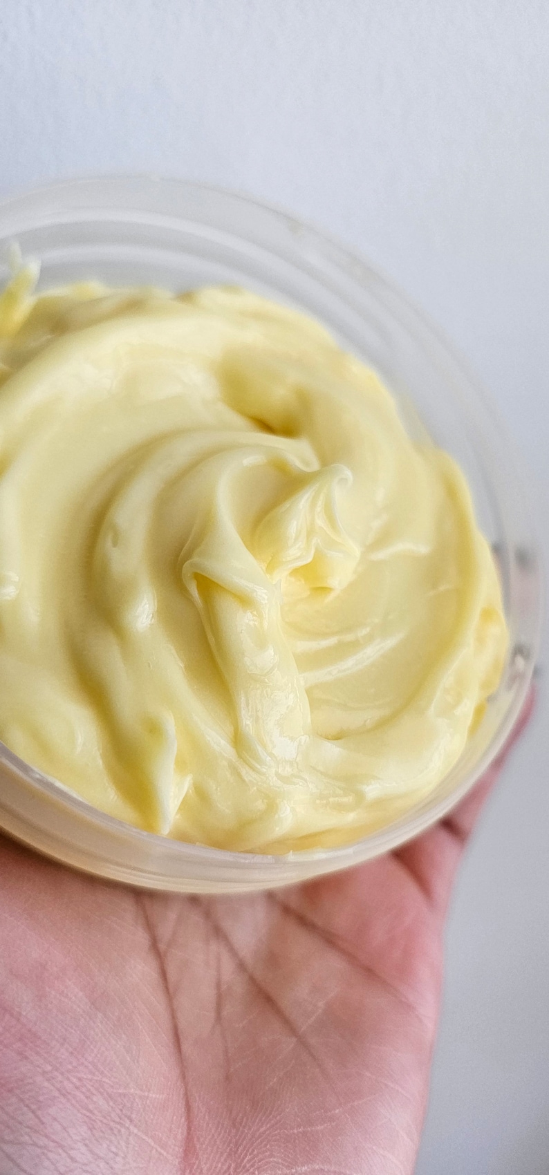 Peut inclure: Gros plan sur un r&eacute;cipient rempli d'une cr&egrave;me lisse de couleur jaune p&acirc;le. La cr&egrave;me est &eacute;paisse et pr&eacute;sente un motif en spirale.