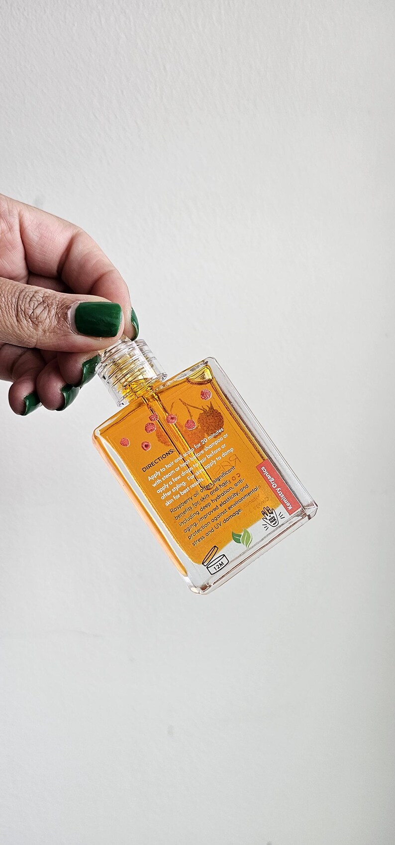 Puede incluir: Una botella rectangular transparente de aceite de frambuesa Kemistry Organics. La botella contiene un l&iacute;quido dorado y tiene una tapa transparente. La etiqueta incluye informaci&oacute;n sobre los beneficios y el uso.