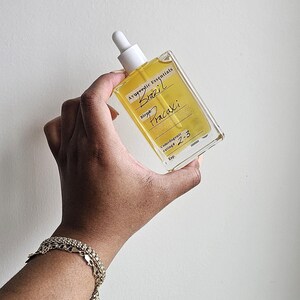 May include: A clear glass bottle with a dropper top filled with a yellow liquid. The bottle has a label that reads "Ayurvedic Essentials Brazil Pracaxi Blend Comedogenic rating 2-3 Exp."