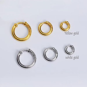 May include: A collection of six hoop earrings arranged in two rows. The top row features three yellow gold hoops of varying sizes, labeled Yellow gold. The bottom row features three silver-toned hoops of varying sizes, labeled white gold.