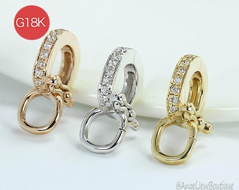 May include: Three gold and silver jewelry clasps with clear gemstones. The clasps have a rounded design with a hinged ring and are set against a white background. The text "G18K" is in a red circle.