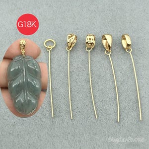 May include: A collection of gold-colored jewelry findings, including bails and a leaf-shaped pendant. The leaf pendant is a translucent green color. The image also includes the text "G18K" in a red circle.