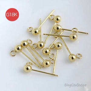 Può includere: Una collezione di perni per orecchini color oro con un design a sfera e anello. I perni sono sottili e dritti, con una piccola sfera a un'estremità e un anello all'altra. L'immagine include un cerchio rosso con la scritta "G18K".