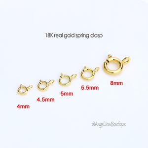 Könnte beinhalten: Auf weißem Hintergrund sind mehrere goldfarbene Federverschlüsse in verschiedenen Größen abgebildet. Die Verschlüsse haben einen Durchmesser von 4 mm bis 8 mm. Der Text lautet "18K real gold spring clasp".