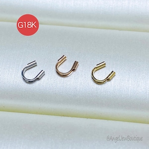 May include: Three horseshoe-shaped ear cuffs in silver, rose gold, and gold. The jewelry pieces are displayed on a white satin surface. A red circle with the text "G18K" is in the upper left corner. The shop's name, "@AngelJewBoutique", is in the lower right corner.
