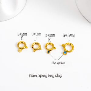 May include: Four gold-colored spring ring clasps, with sizes and letters labeled. One clasp has a blue sapphire. The text "Secure Spring Ring Clasp" is below the clasps.