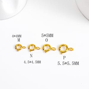 May include: Four gold-colored spring clasp jewelry findings in varying sizes. The smallest is 4x4mm, and the largest is 5.5x5.5mm. Each clasp has a circular ring and a lever for secure closure. Text indicates sizes.