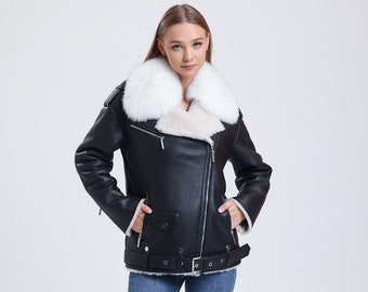 May include: A black leather jacket with a white fur collar and a belt. The jacket has a zipper closure and two pockets. The model is wearing blue jeans and white sneakers.