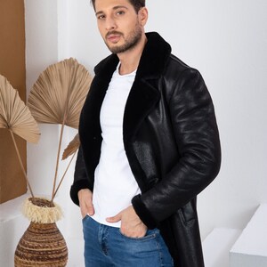 Puede incluir: Un hombre con una chaqueta de cuero negra con cuello de piel y pantalones vaqueros azules. La chaqueta tiene una cremallera y dos bolsillos.