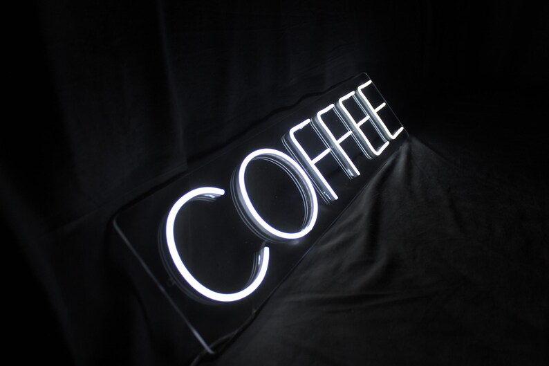 May include: White neon sign with the word "COFFEE" in a black frame.
