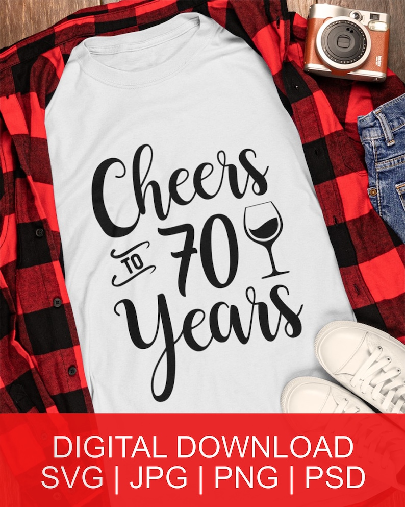 May include: White t-shirt with black text that reads "Cheers to 70 Years" and a black silhouette of a wine glass.