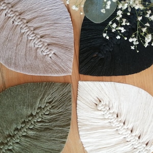Könnte beinhalten: Vier handgefertigte Makramee-Wandbehänge in Form von Blättern in Beige, Schwarz, Grün und Weiß.