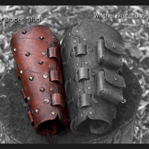 May include: Two leather bracers, one brown with metal studs and the other black with pockets, labelled "Witcher Bracer Stud" and "Witcher Bracer UnoPurse".