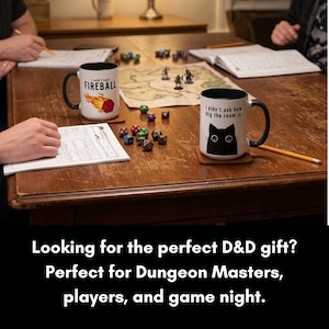 K&ouml;nnte beinhalten: Zwei wei&szlig;e Keramiktassen mit schwarzen Henkeln und Innenseiten. Eine Tasse zeigt eine Feuerball-Grafik und den Text I said I cast FIREBALL. Die andere Tasse zeigt eine schwarze Katzenillustration und den Text I didn't ask how big the room is.