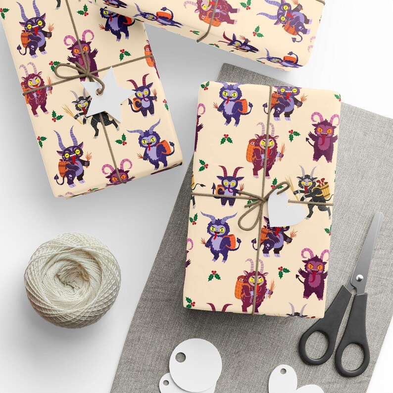 Sheets of Krampus wrapping paper with cartoon Krampuses on beige background, tied with string next to scissors and gift tags