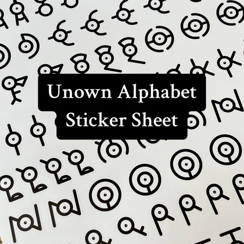 May include: A sheet of stickers featuring the Unown alphabet from the Pokemon franchise. The stickers are black and white and feature the Unown characters in a variety of poses. The sheet is labeled "Unown Alphabet Sticker Sheet".