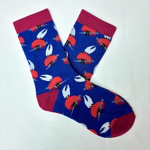 May include: A pair of blue socks featuring a repeating pattern of red crab claws and white claws. The heel, toe, and cuff are a deep red. The socks are displayed on a white surface.