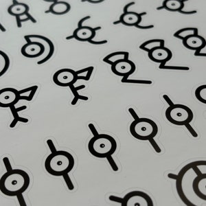 May include: A sheet of black and white stickers featuring various designs, including a stylized eye with a line through it, a bird-like creature, and a stylized eye with a curved line through it.